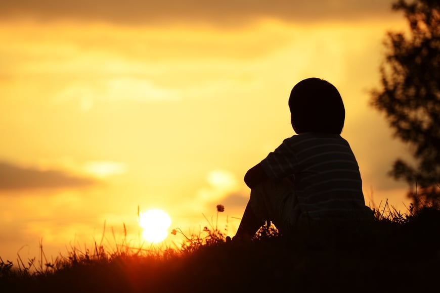 Image of a young boy looking looking at a sunset